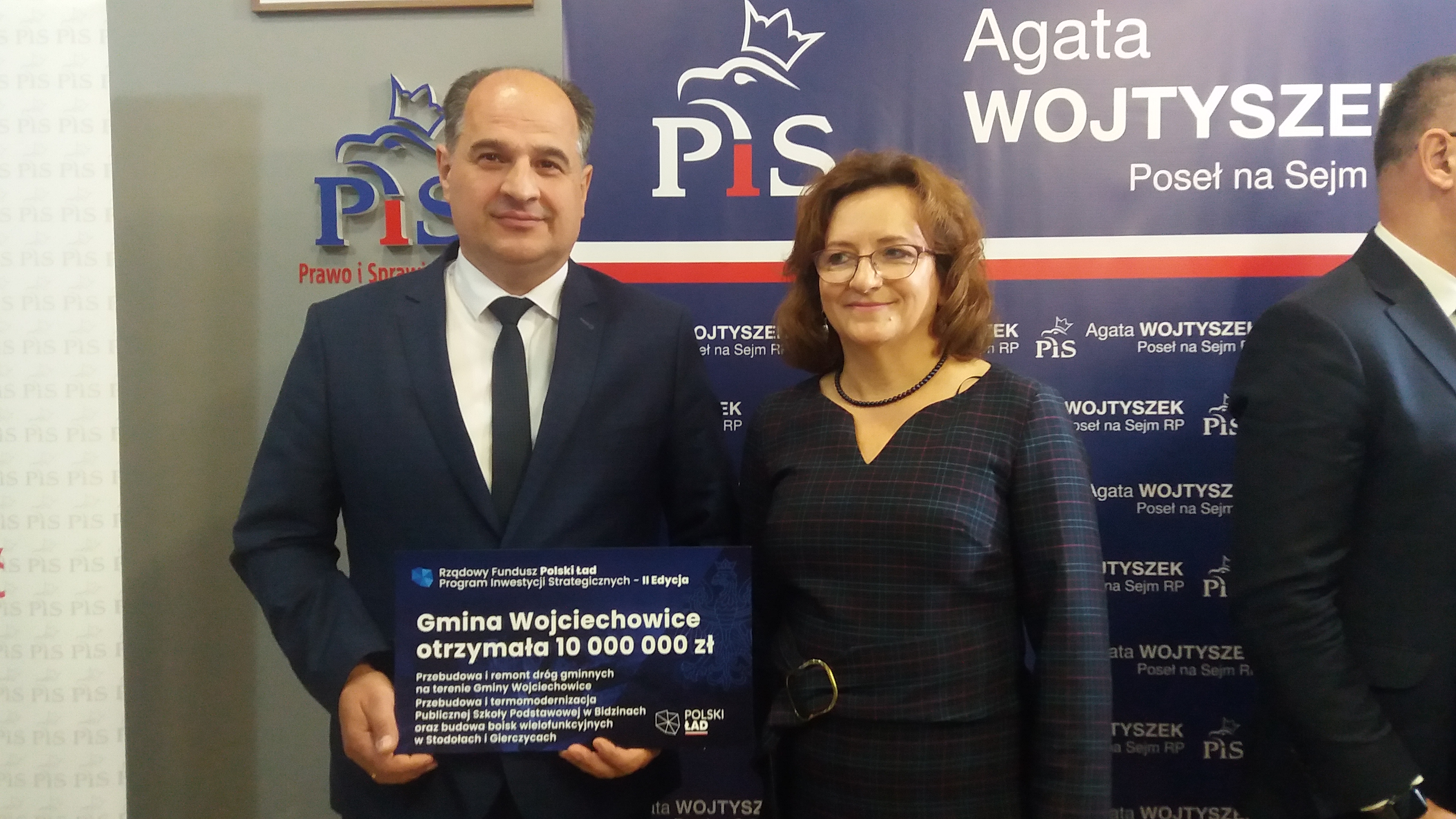 Wójt Gminy Wojciechowice Szymon Sidor trzymający w rękach promese na realizację zadań z Rządowego Funduszu Polski Ład wraz z Panią Poseł Agatą Wojtyszek pozują do zdjęcia.