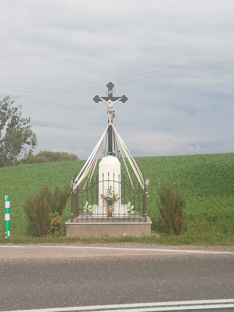 Krzyż metalowy na postumencie murowanym znajduję się na skrzyżowaniu drogi krajowej Nr 74 i drogi powiatowej Nr 0734T po prawej stronie w kierunku Kielc