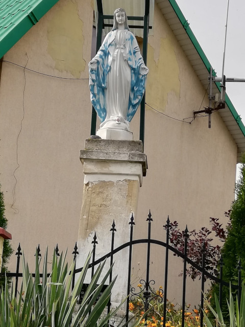 Figurka Matki Boskiej usytuowana na murowanym postumencie zlokalizowanym przy drodze gminnej Nr 004491T Stodoły-Wieś – Podlisów w miejscowości Stodoły-Wieś