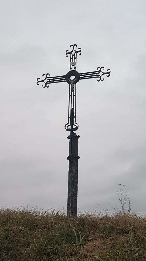 Krzyż metalowy usytuowany na skarpie przy drodze krajowej DK 74 po prawej stronie w kierunku Opatowa