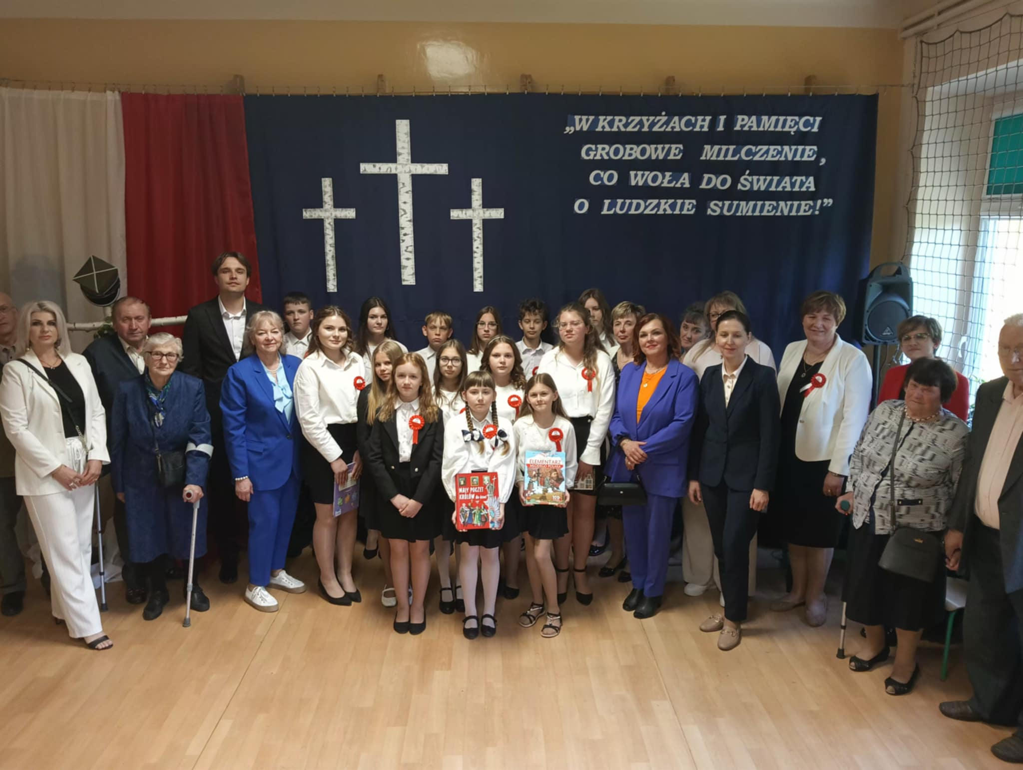 Zdjęcie grupowe uczestników uroczystości na tle dekoracji patriotycznych