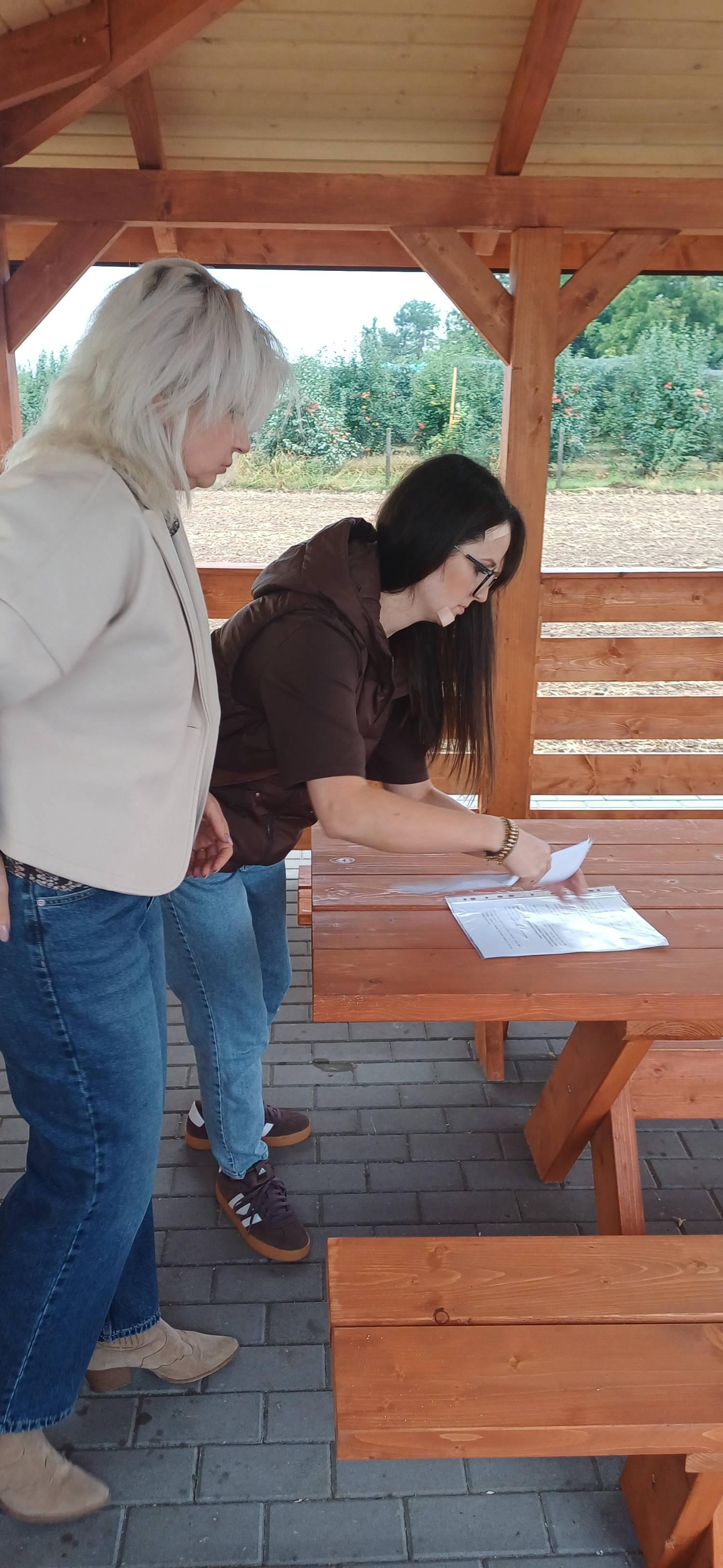 Odbiór altanki z wyposażeniem przy świetlicy wiejskiej w Orłowinach Sołtys Orłowin i pracownik Gminy przy podpisywaniu dokumentów w altanie