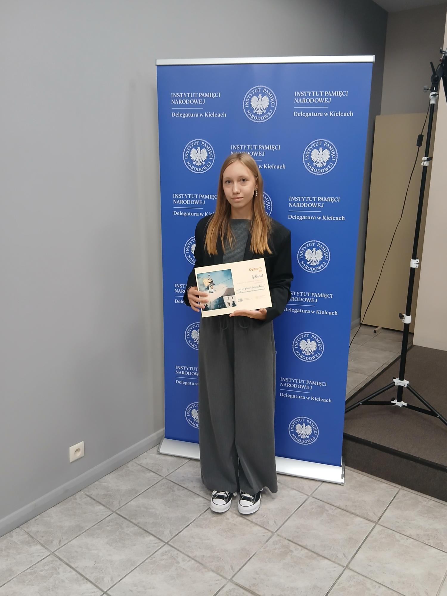 Uczestniczka konkursu na tle roll up'a Instytut Pamięci Narodowej Delegatura w Kielcach