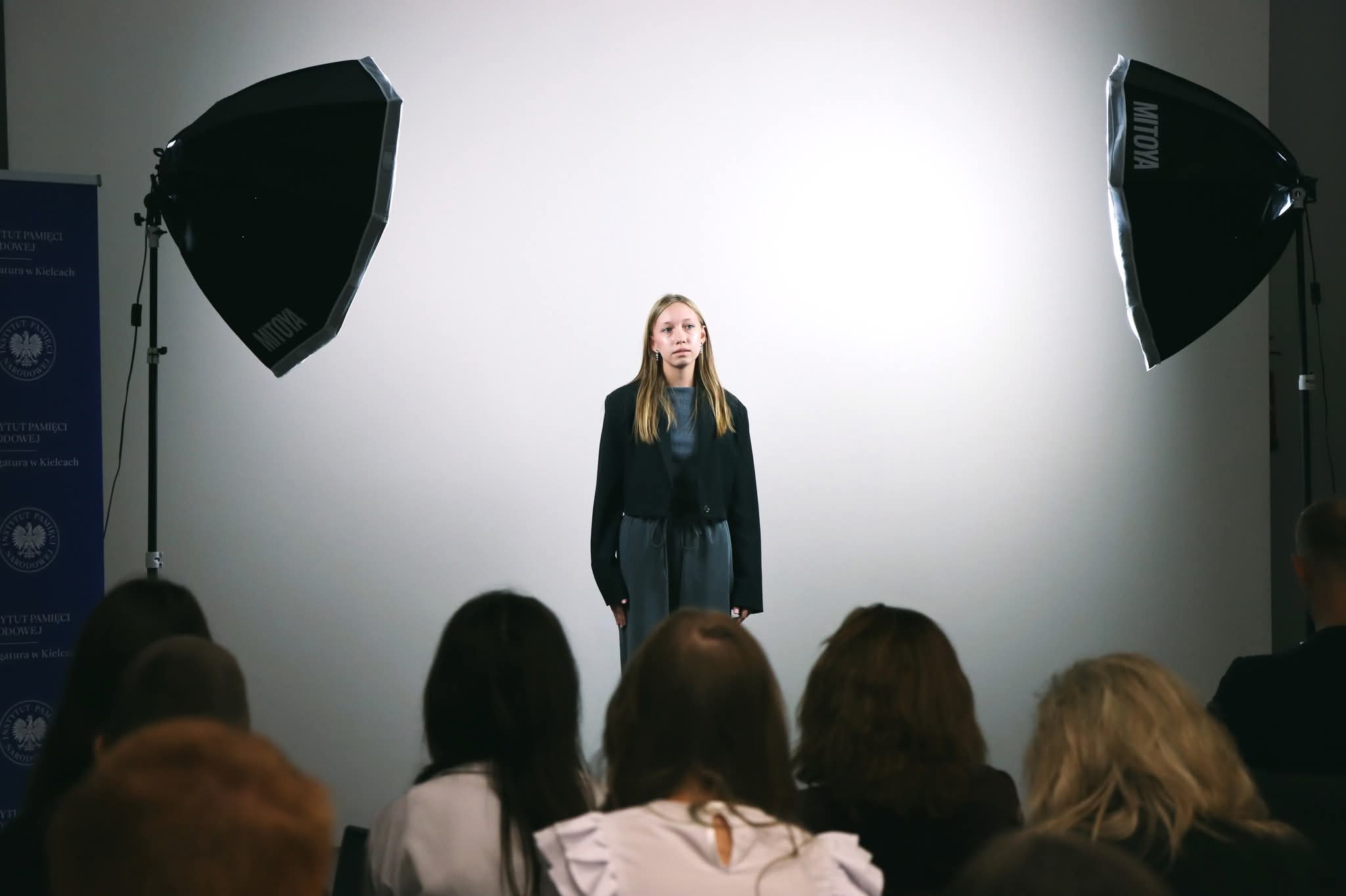Uczestniczka konkursu w trakcie występu. Widoczna widownia oraz lampy oświetlające