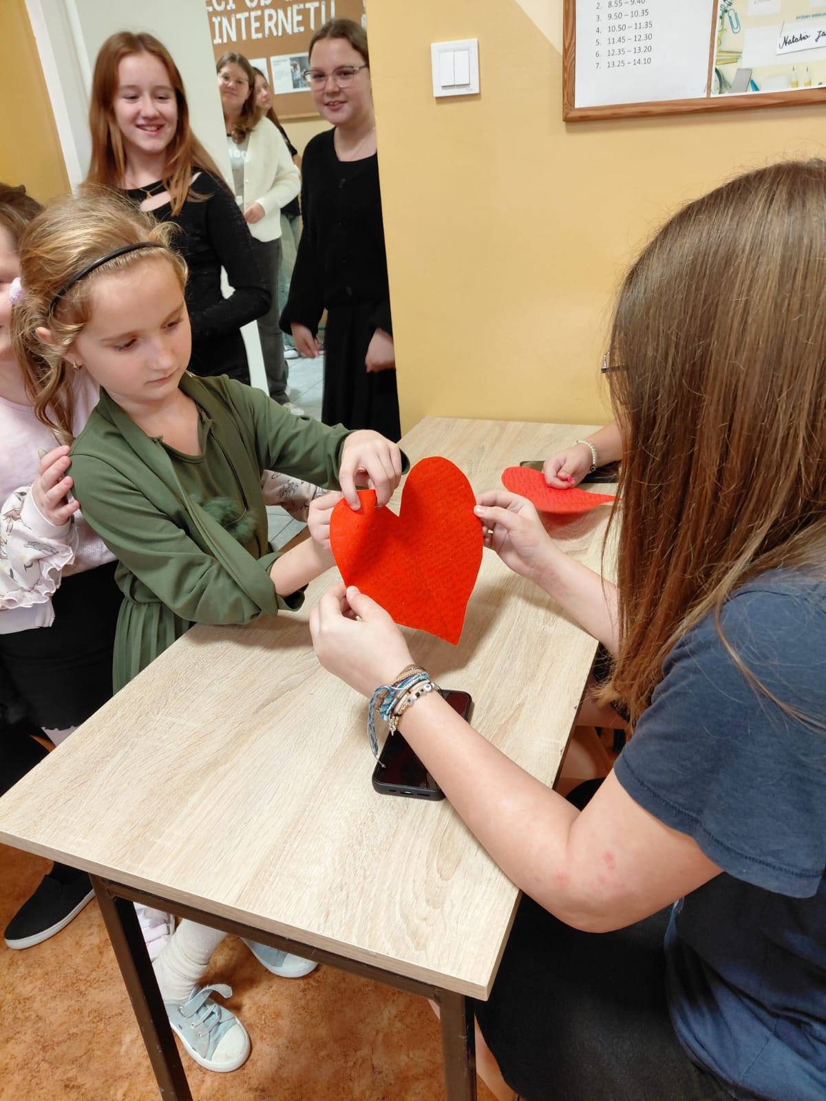 Uczennica przebija szpilką czerwone papierowe serce