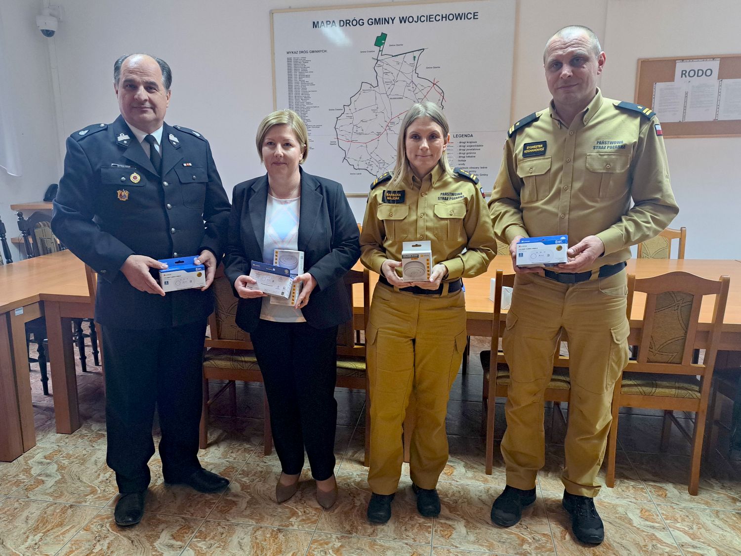 W&oacute;jt Gminy, Komendant PSP, Zastępca Komendanta PSP oraz Kierownik OPS trzymają w rękach czujniki