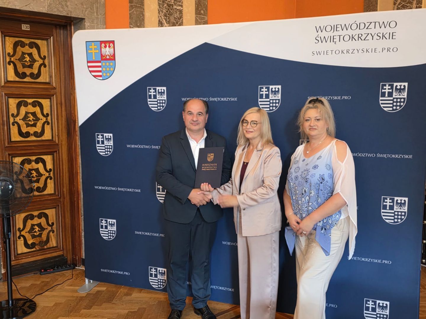 Podpisanie umowy na modernizację drogi w Mierzanowicach Wójt Gminy Wojciechowice i Marszałek Województwa podczas uścisku dłoni, obok Skarbnik Gminy