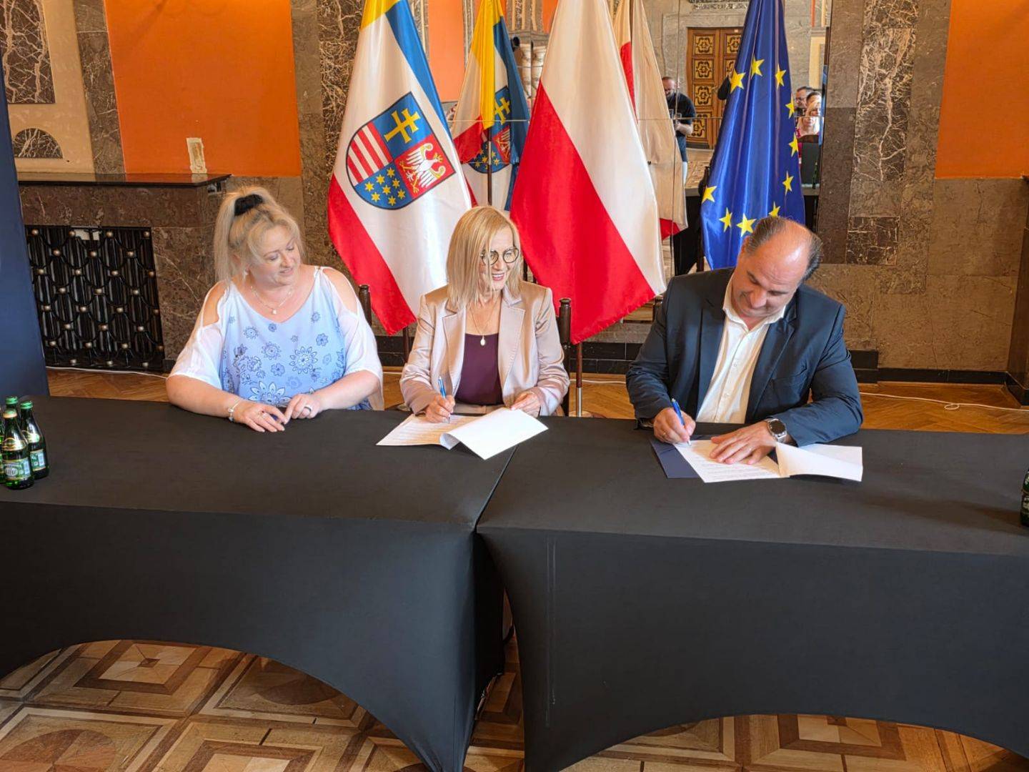 Podpisanie umowy na modernizację drogi w Mierzanowicach Od lewej Skarbnik Gminy, Marszałek Województwa i Wójt Gminy siedzą przy stole podczas podpisania umowy